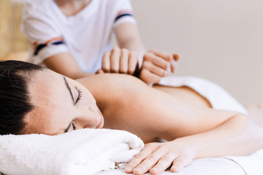 Pessoa deitada recebendo uma massagem vigorosa nas costas.